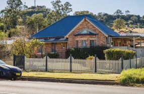 Brick exterior home with white picket fence